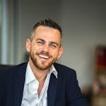 Business professional in suit smiling confidently in a modern office environment.