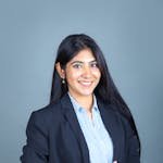 Confident woman in business suit smiling with a formal pose against a neutral background