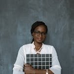 Professional woman standing with a grid board against a textured background.